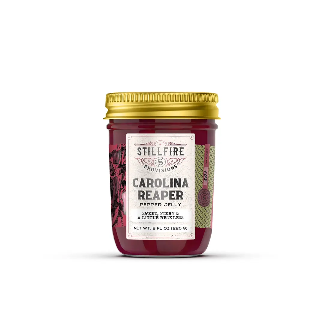 Jar of Carolina Reaper pepper jelly with a gold lid on a white background