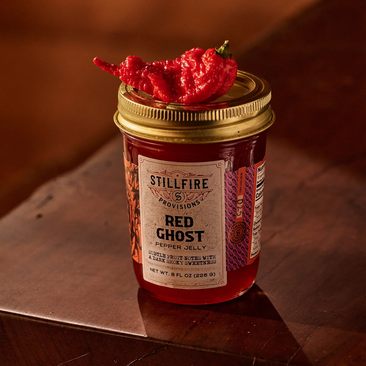 Red Ghost Pepper Jelly with a Red Ghost Pepper on top of the jar.