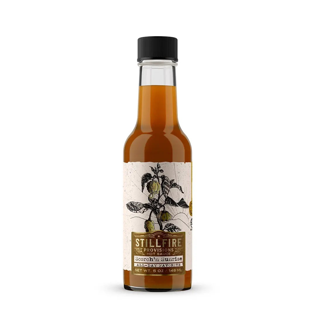 Bottle of Stillfire Provisions Scorch'n Sunrise hot sauce on a white background