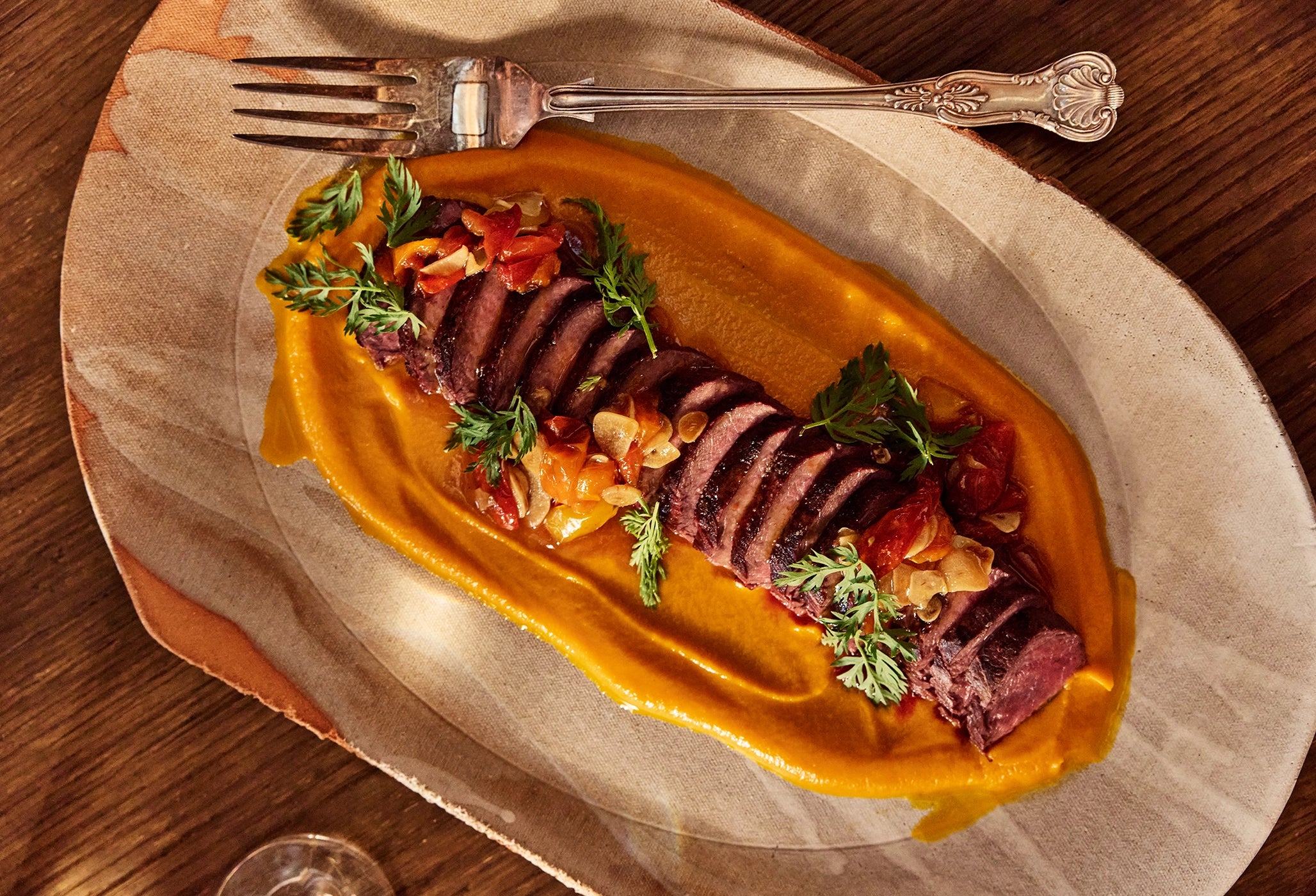 Plated dish of sliced meat with vegetables on a wooden table