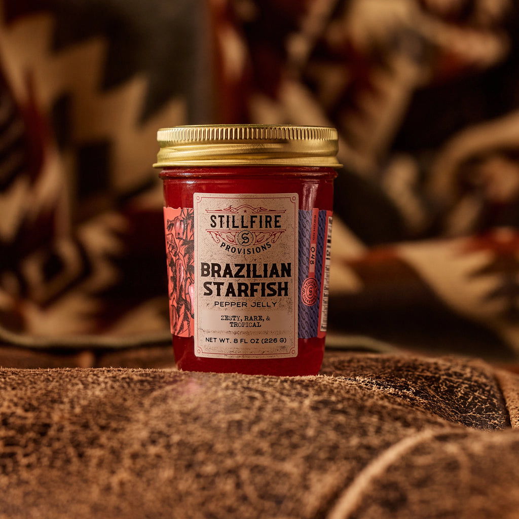 Brazilian Starfish Pepper Jelly on worn leather couch with a southwestern blanket behind it.