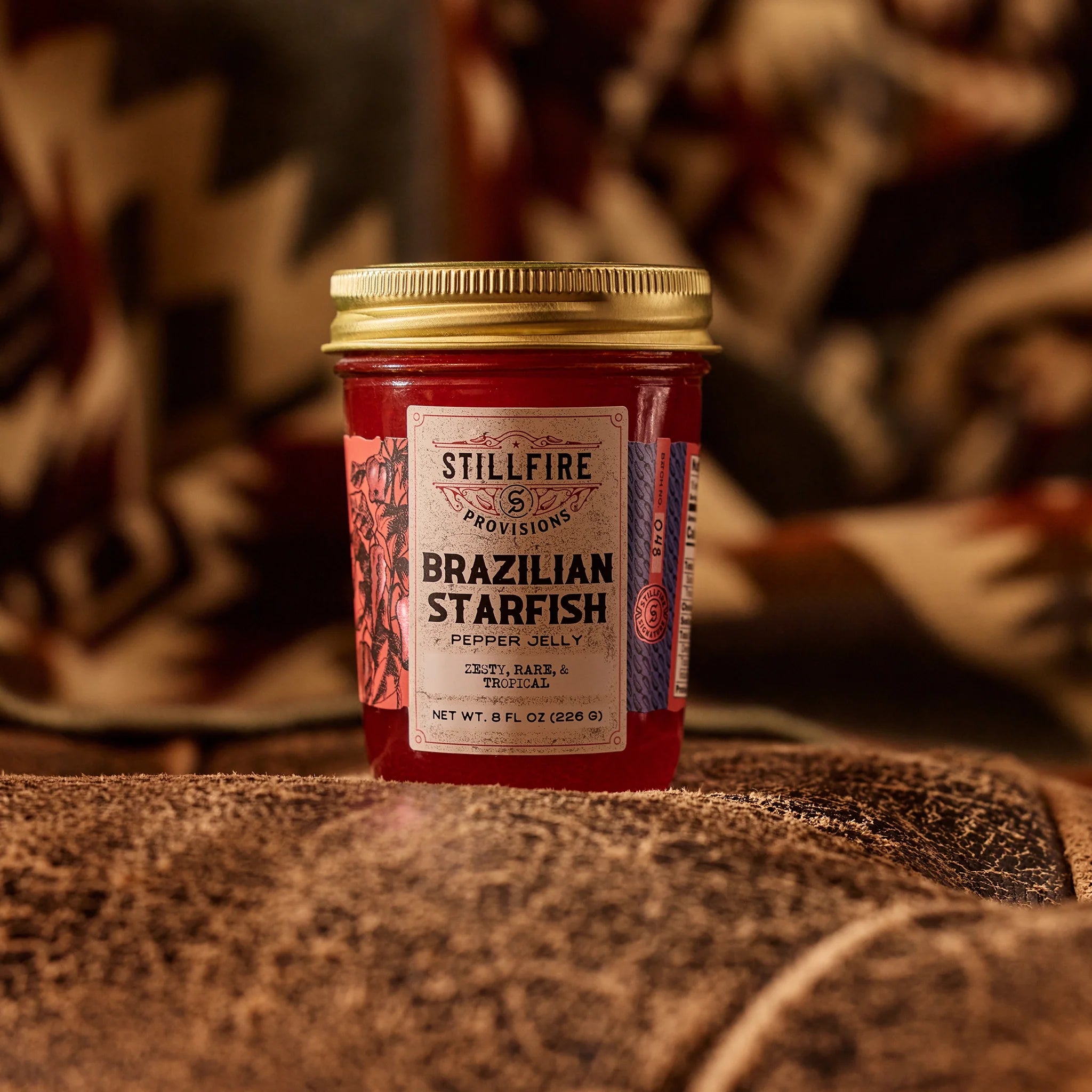 Brazilian Starfish Pepper Jelly on worn leather couch with a southwestern blanket behind it.