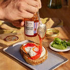 Brazilian Starfish Pepper Jelly being spooned over a burrata cheese on toast by a professional chef.