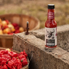 Carolina Reaper Hot Sauce next to hot peppers in baskets