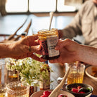 Chocolate Habanero Pepper Jelly jar passed between two people at dinner.