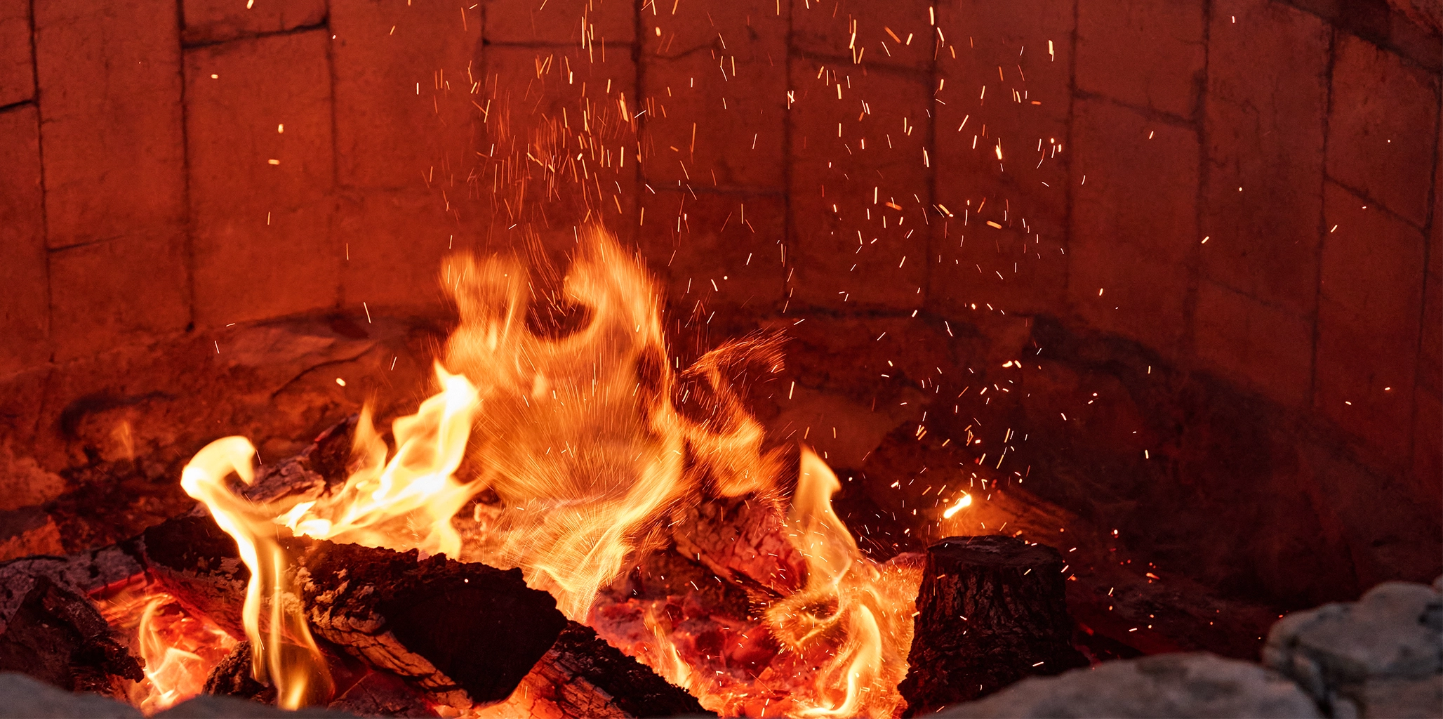 Fire burning in a brick fireplace with flames and embers.
