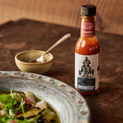 Ghost Pepper Hot Sauce next to a gourmet dinner plate on a table.
