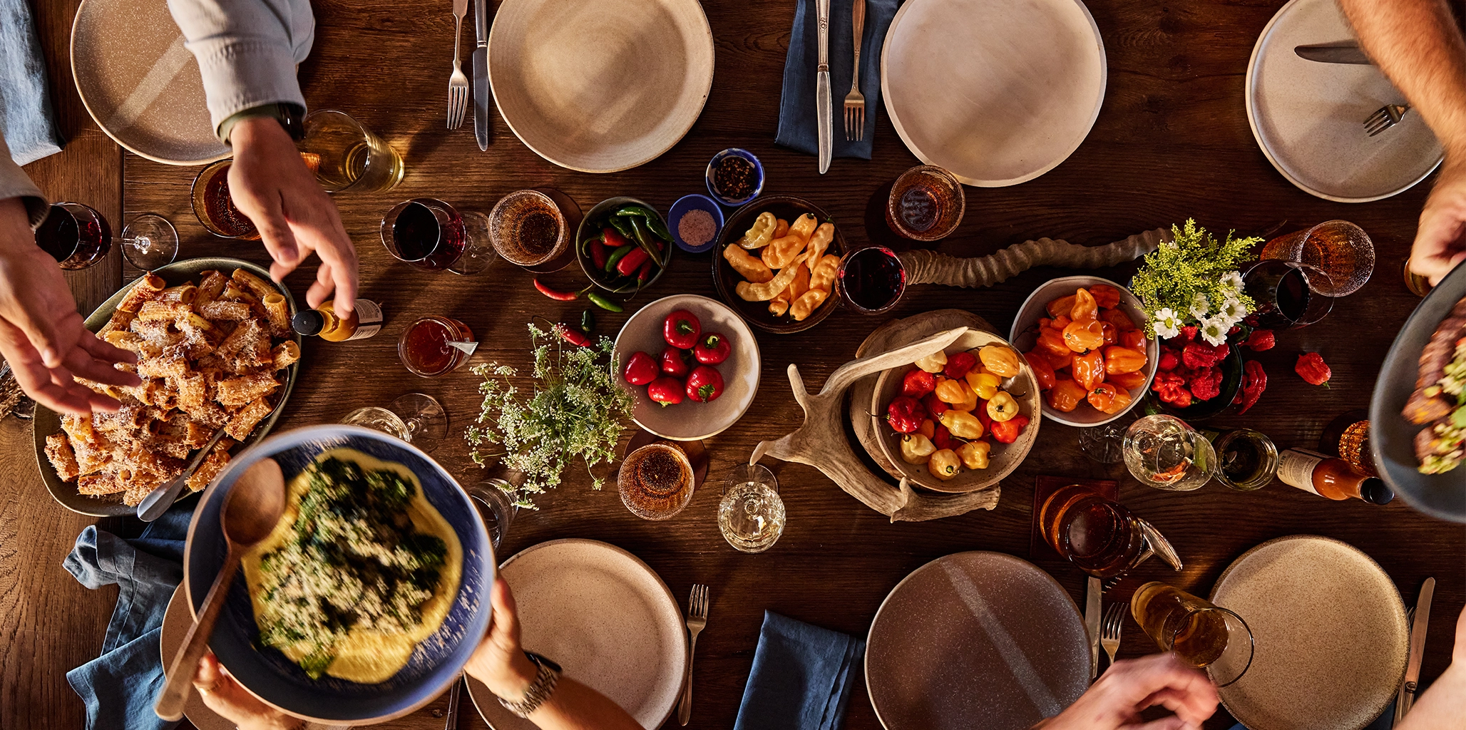 Top-down view of a wooden dining table set with plates, bowls, and food.