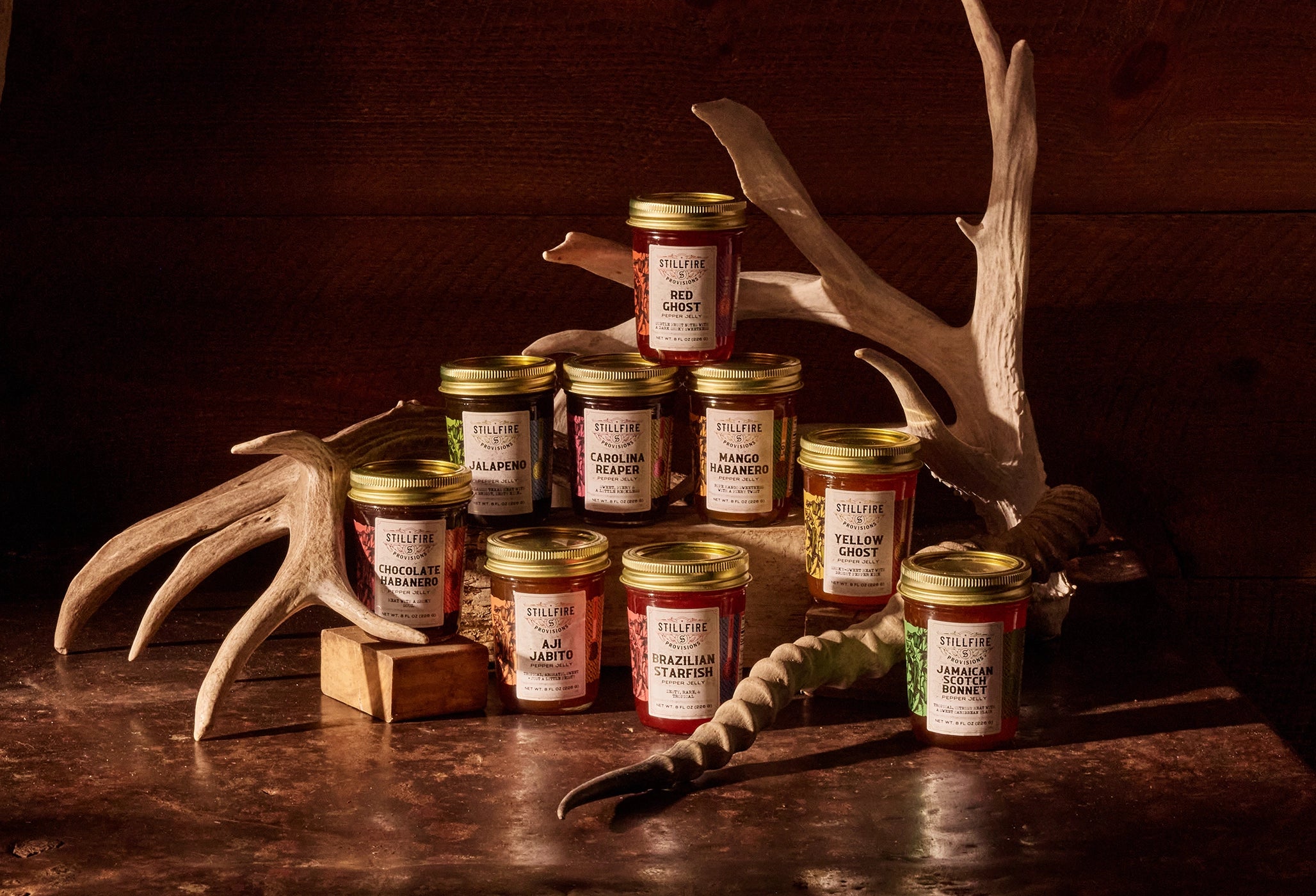 Jars of jelly arranged on a wooden surface with deer antlers in the background