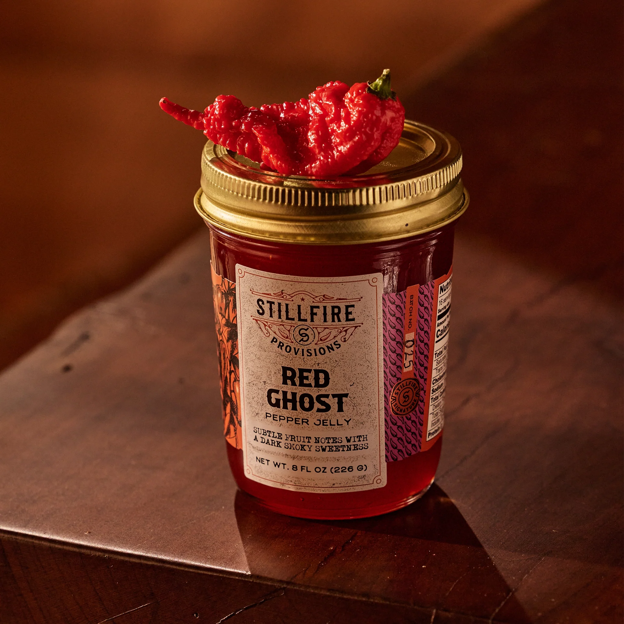 Red Ghost Pepper Jelly with a Red Ghost Pepper on top of the jar.