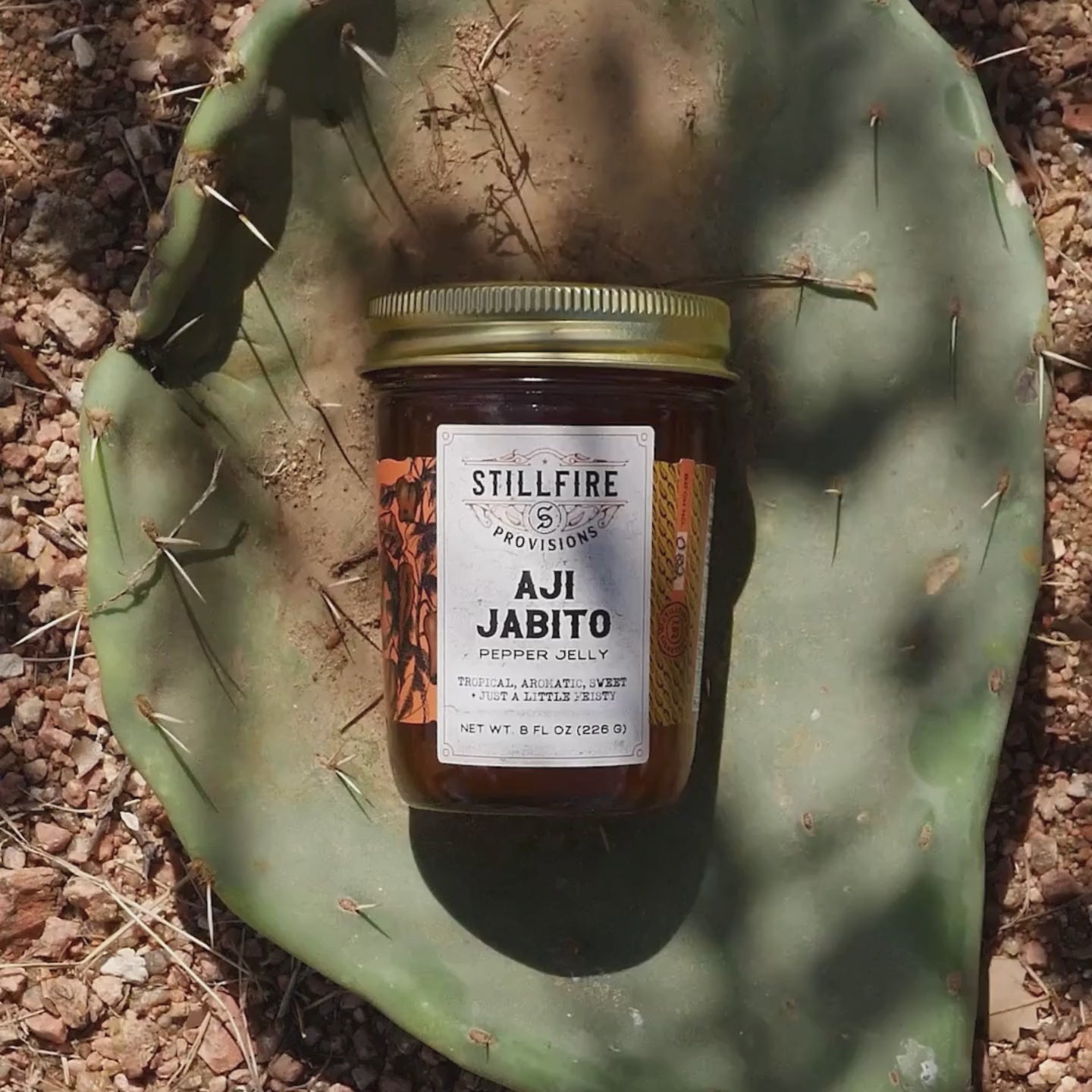 Aji Jabito Pepper Jelly in a jar, shown on a cactus-themed background.