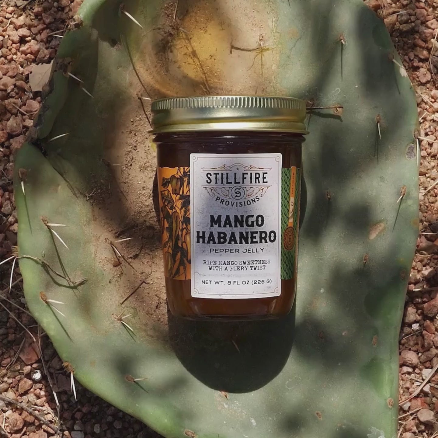 Mango Habanero Pepper Jelly in a jar, shown on a cactus-themed background.