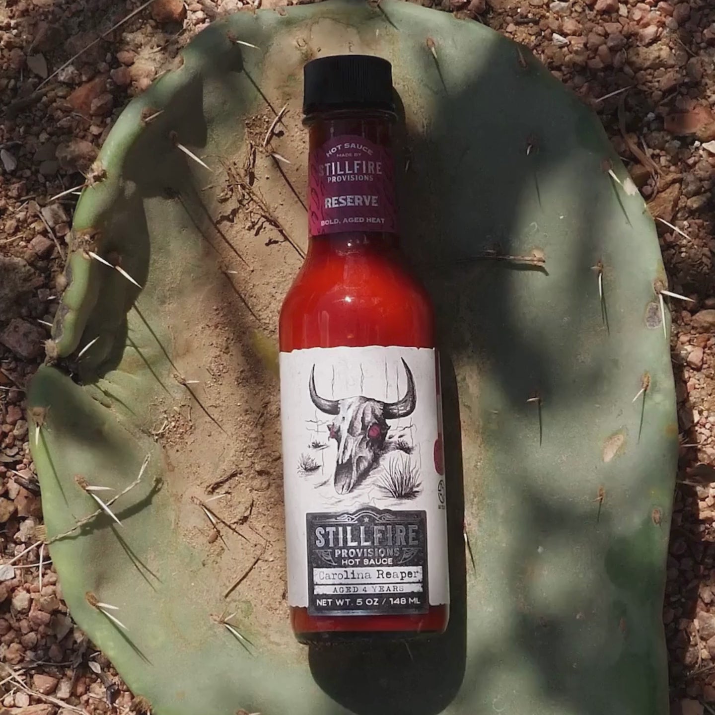 Carolina Reaper hot sauce, shown on a cactus-themed background.